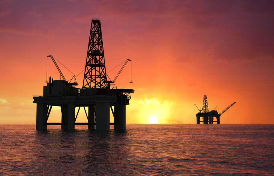 Oil rig silhouette over orange sky