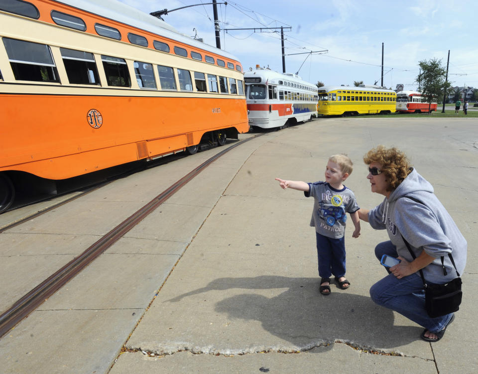 In this Sept. 28, 2013 photo, Johnathan Sainski, 2, of Wheatland, Wis., points out his favorite streetcar to his grandmother Anna Sainski, of Bristol, Wis., during Kenosha Streetcar Day outside the Joseph McCarthy Transit Center in Kenosha, Wis. From left are the Johnstown (Kenosha), Southeastern Pennsylvania, Cincinnati and the Pittsburgh streetcars. When the city of Kenosha lost the auto plant that employed thousands, the a bruised community in southern Wisconsin plucked something unexpected from its pre-automobile past to help reinvent the city and fill its depressed downtown with life. They brought back their street cars, sending brightly colored antique trolleys creeping along a two-mile loop around the city and along the lake Michigan shore. (AP Photo/Michael Schmidt)