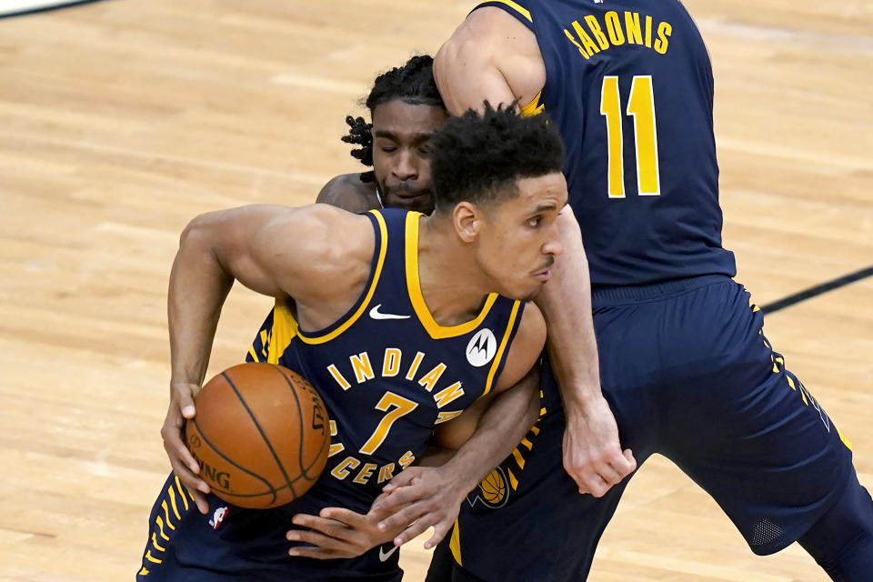 Chicago Bulls' Coby White is sandwiched between Indiana Pacers' Malcolm Brogdon (7) and a pick set by Domantas Sabonis during the second half of an NBA basketball game Saturday, Dec. 26, 2020, in Chicago. (AP Photo/Charles Rex Arbogast)
