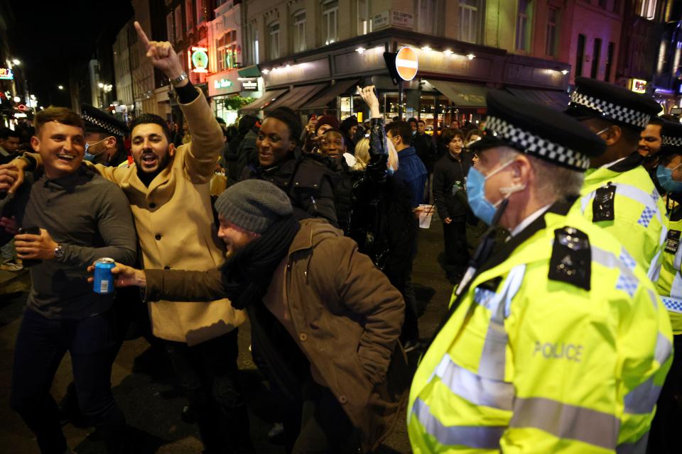 People in the street while police officers look on as pubs close ahead of the second national lockdown, in Soho, London (REUTERS)