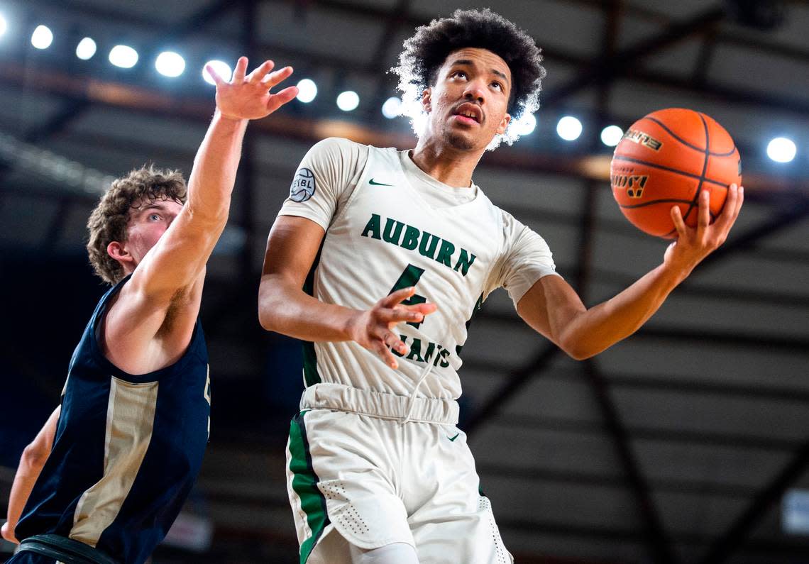 Auburn forward Semaj Brown (4) jumps to make an underhanded layup as Arlington forward David Zachman (14) tries to block him during an opening round game at the WIAA state basketball tournament in the Tacoma Dome in Tacoma, Washington, on Wednesday, March 1, 2023. Auburn won the game 52-41.