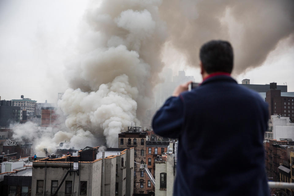NEW YORK, NY - MARCH 26:  A local resident takes a picture as building burns after an explosion on 2nd Avenue of Manhatten's East Village on March 26, 2015 in New York City. Officials have reported that at least 12 people were injured but it is unclear if anyone was trapped inside either building.   (Photo by Andrew Burton/Getty Images)