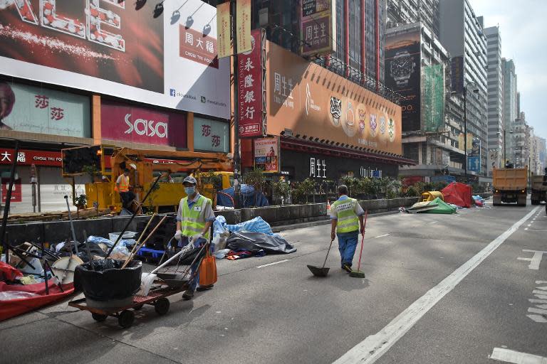 Workers clean a road, previously occupied by pro-democracy protesters, after police completed their clearance of a protest site in the Mongkok district of Hong Kong, on November 26, 2014