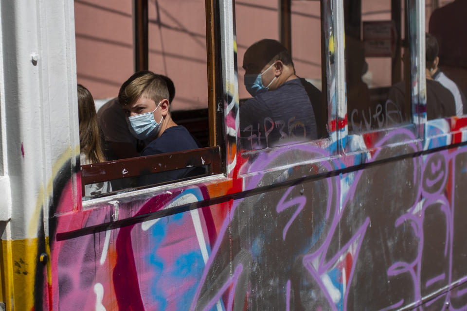 Passengers wear face masks for protection against the new coronavirus while riding on a tram in Lisbon, Portugal, Friday, Aug. 14, 2020. Portuguese health authorities have advised people to wear face masks when using public transport to help stem the spread of COVID-19. (AP Photo/Manu Fernandez)