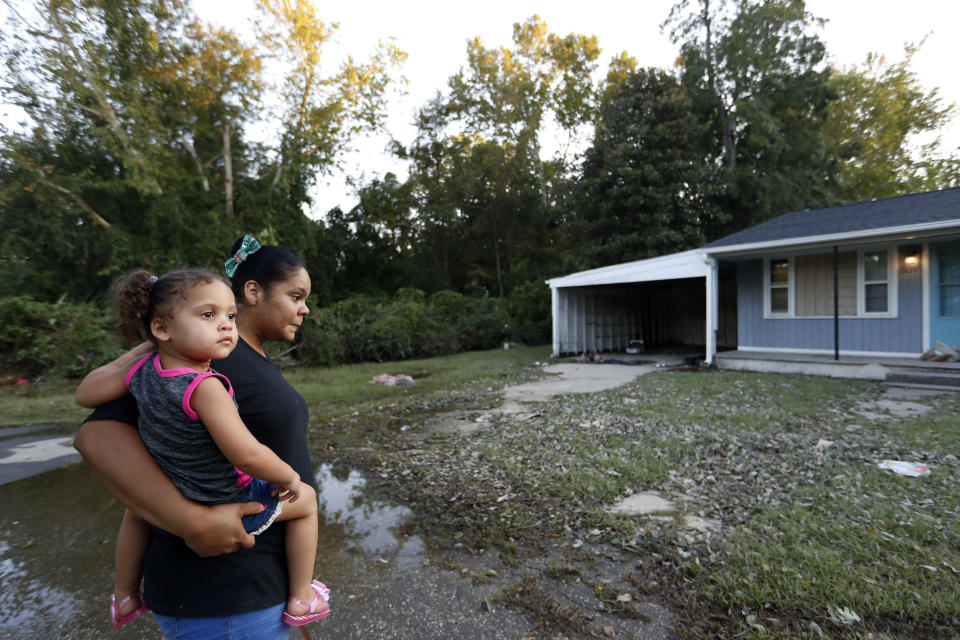 Rosemary Acevedo-Gonzalez, left, holds her daughter, Jordalis, 2, as they return to their home for the first time since it was flooded in the aftermath of Hurricane Florence in Spring Lake, N.C., Wednesday, Sept. 19, 2018. (AP Photo/David Goldman)