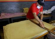 A worker cuts the dough of pastry sheets of sambusa snacks during the holy month of Ramadan in Sanaa