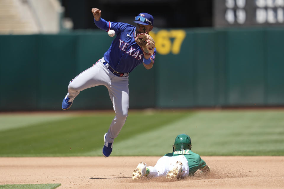 Oakland Athletics' Esteury Ruiz, bottom, steals second base under Texas Rangers second baseman Marcus Semien during the fourth inning of a baseball game in Oakland, Calif., Saturday, May 13, 2023. (AP Photo/Jeff Chiu)