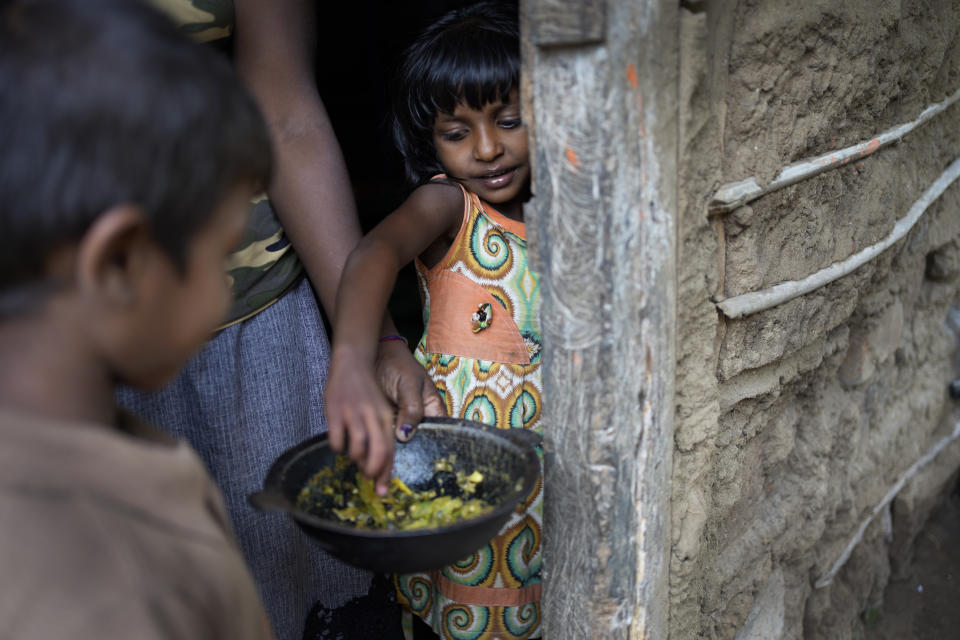 Sulochana Madushani, right, eats Okara curry from a pot at Mahadamana village in Dimbulagala, about 200 kilometres northeast of Colombo, Sri Lanka, Sunday, Dec. 11, 2022. Due to Sri Lanka's current economic crisis families across the nation have been forced to cut back on food and other vital items because of shortages of money and high inflation. Many families say that they can barely manage one or two meals a day. (AP Photo/Eranga Jayawardena)