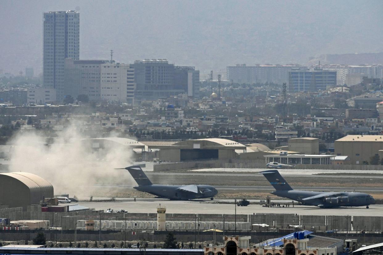 US soldiers stand on the tarmac as US Air Force aircraft (L) prepares for take-off from the airport in Kabul, Afghanistan on Aug. 30, 2021.