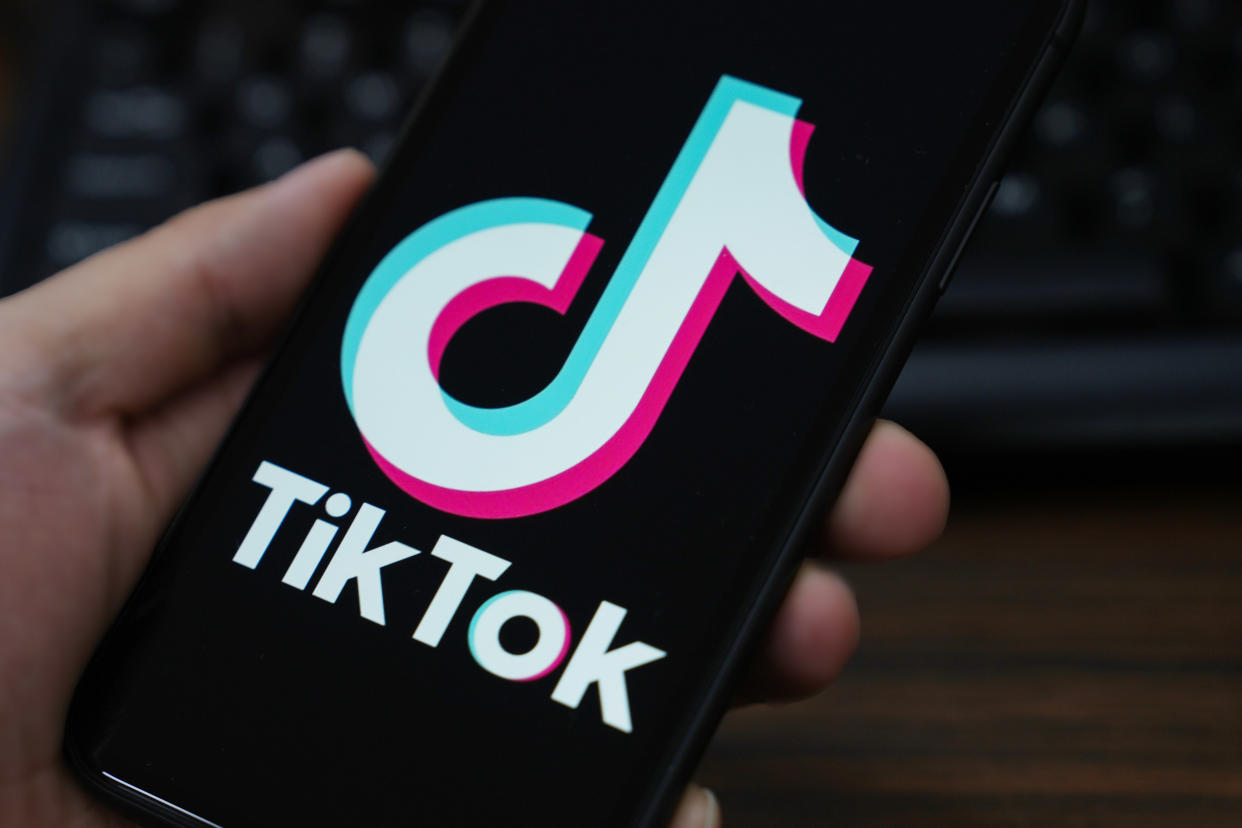 Hand mit Smartphone und großem TikTok-Logo