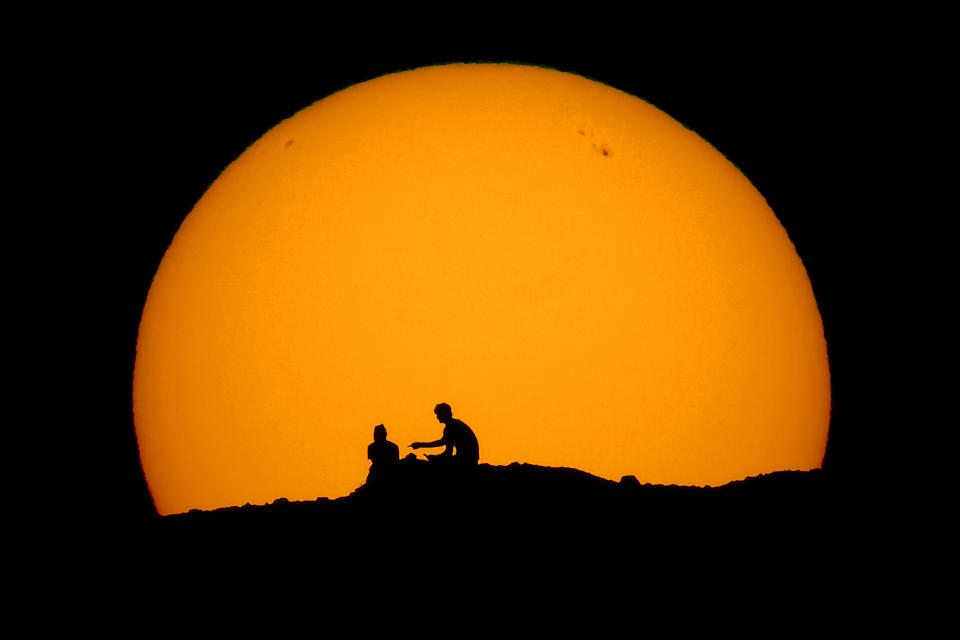 Hikers are silhouetted against the setting sun at Papago park in Phoenix on Feb. 18, 2023. (AP Photo/Charlie Riedel)