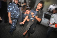 A Palestinian man carries a child into the treatment room of Shifa hospital following an Israeli airstrike, in Gaza City, Friday, Nov. 16, 2012. (AP Photo/Ashraf Amra)