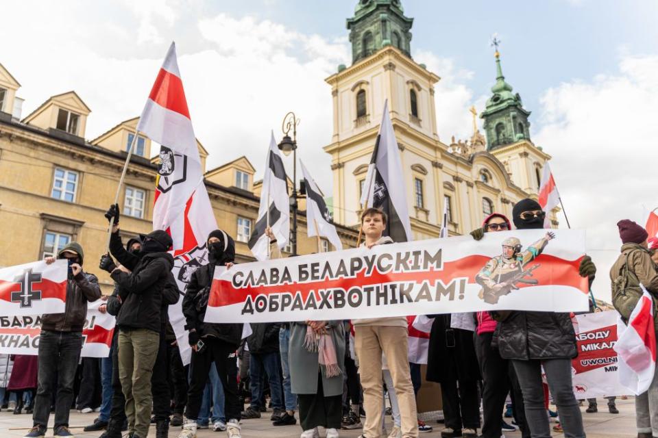 Protesters wave flags used by the Belarus opposition and hold a banner that says "Glory to the Belarusian volunteers" (fighting in the Armed Forces of Ukraine). On March 24, a protest took place with hundreds participating, commemorating the 106th anniversary of the declaration of independence by the Belarusian People's Republic, a short-lived unrecognized state during World War I. (Marek Antoni Iwanczuk/SOPA Images/LightRocket via Getty Images)