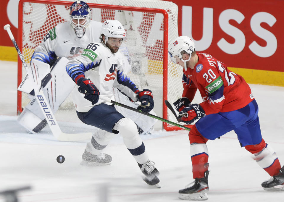 Christian Wolanin of the US, centre, challenges for the puck with Norway's Emilio Pettersen during the Ice Hockey World Championship group B match between Norway and United States at the Arena in Riga, Latvia, Saturday, May 29, 2021. (AP Photo/Sergei Grits)