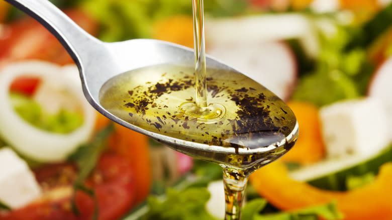 Olive oil poured onto spoon with vegetables 