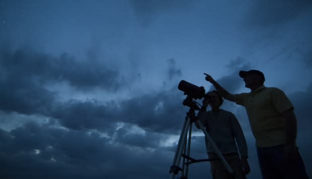 Couple using telescope on tripod