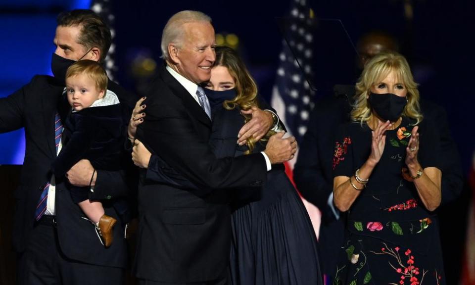 Joe Biden hugs one of his granddaughters as he stands with grandson and son Hunter Biden (L) and wife Jill Biden on Saturday