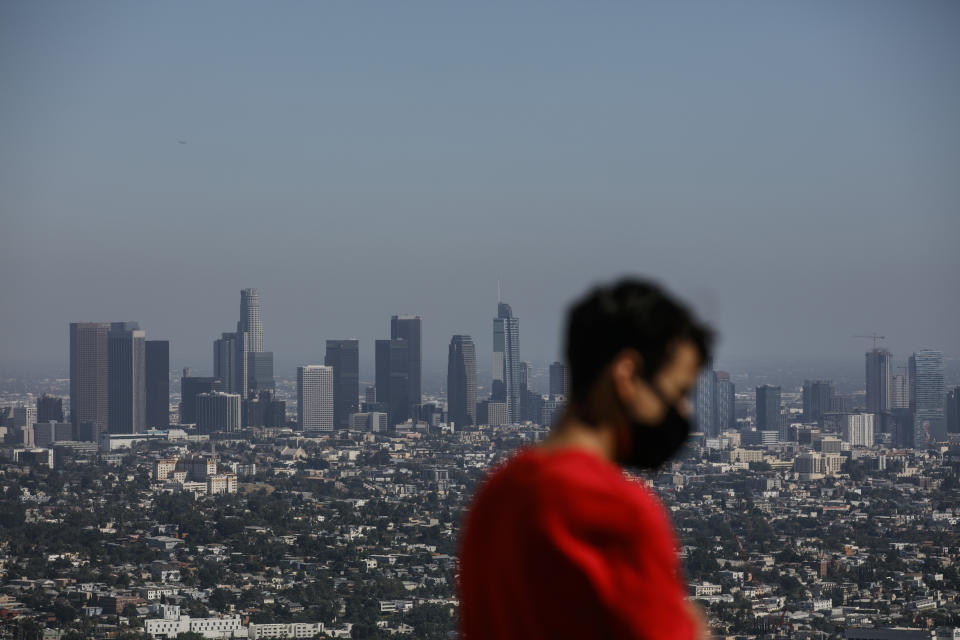 Izzy Galvan, 20, wears a face mask while visiting the Griffith Observatory overlooking downtown Los Angeles, Wednesday, July 15, 2020, in Los Angeles. Coronavirus cases have surged to record levels in the Los Angeles area, putting the nation's largest county in "an alarming and dangerous phase" that if not reversed could overwhelm intensive care units and usher in more sweeping closures, health officials said Wednesday. (AP Photo/Jae C. Hong)