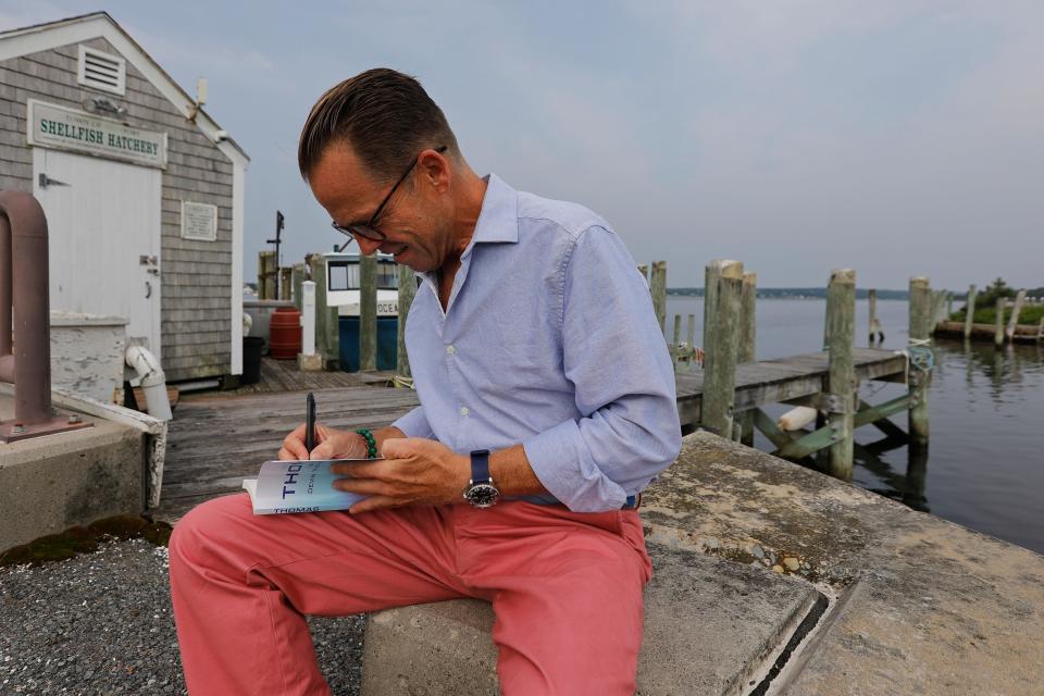 Devin Thomas Corey signs a copy of his book, "Thomas," while sitting at Westport Point.