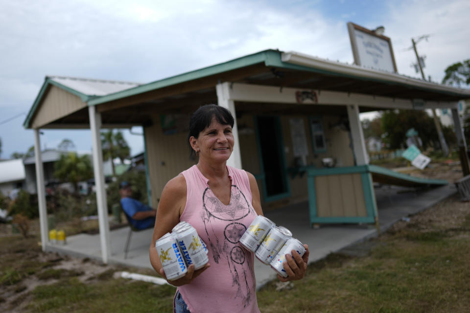 Renee Futch holds water provided by a team from the American Red Cross, outside the storm-damaged live bait business she owns with her husband, "Florida Cracker Shrimp & Bait Co.," in Horseshoe Beach, Fla., Friday, Sept. 1, 2023, two days after the passage of Hurricane Idalia. (AP Photo/Rebecca Blackwell)