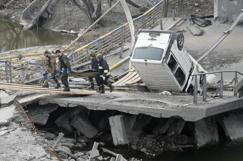 Ukrainian soldiers carry a body of a civilian killed by the Russian forces over the destroyed bridge in Irpin close to Kyiv, Ukraine, Thursday, March 31, 2022. The more than month-old war has killed thousands and driven more than 10 million Ukrainians from their homes including almost 4 million from their country. (AP Photo/Efrem Lukatsky)