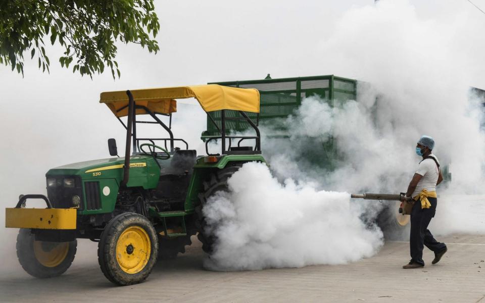 A volunteer sprays disinfectant to sanitise a wholesale grain market amidst rising Covid-19 cases - NARINDER NANU / AFP