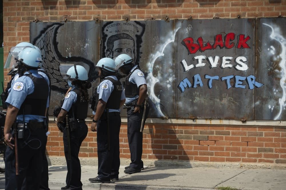 Police officers stand beside a mural for George Floyd in the Chicago neighborhood of Bronzeville during an anti-police brutality protest. (Pat Nabong/Chicago Sun-Times via AP, File)