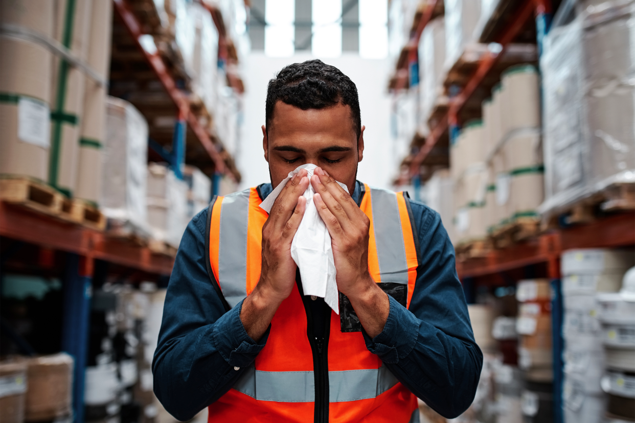 employee blowing nose in a warehouse