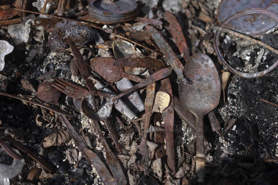 Burnt spoons, forks and knives lie on the ground among the remains of Julia Cardinal's cabin that was destroyed by wildfires, near Fort Chipewyan, Canada, on Sunday, Sep. 3, 2023. Cardinal lost the riverside cabin that was many things to her: retirement project, gift from from her husband, and somewhere to live by nature, as her family had done for generations. (AP Photo/Victor R. Caivano)