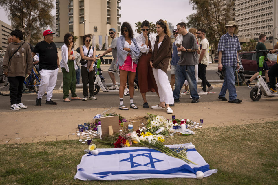 People gather and lay flowers at the site where Alessandro Parini, an Italian tourist, was killed in a Palestinian attack, in Tel Aviv, Israel, Saturday, April 8, 2023. Israeli authorities said an Italian tourist was killed and five other Italian and British citizens were wounded Friday when a car rammed into a group of tourists in Tel Aviv. (AP Photo/Oded Balilty)