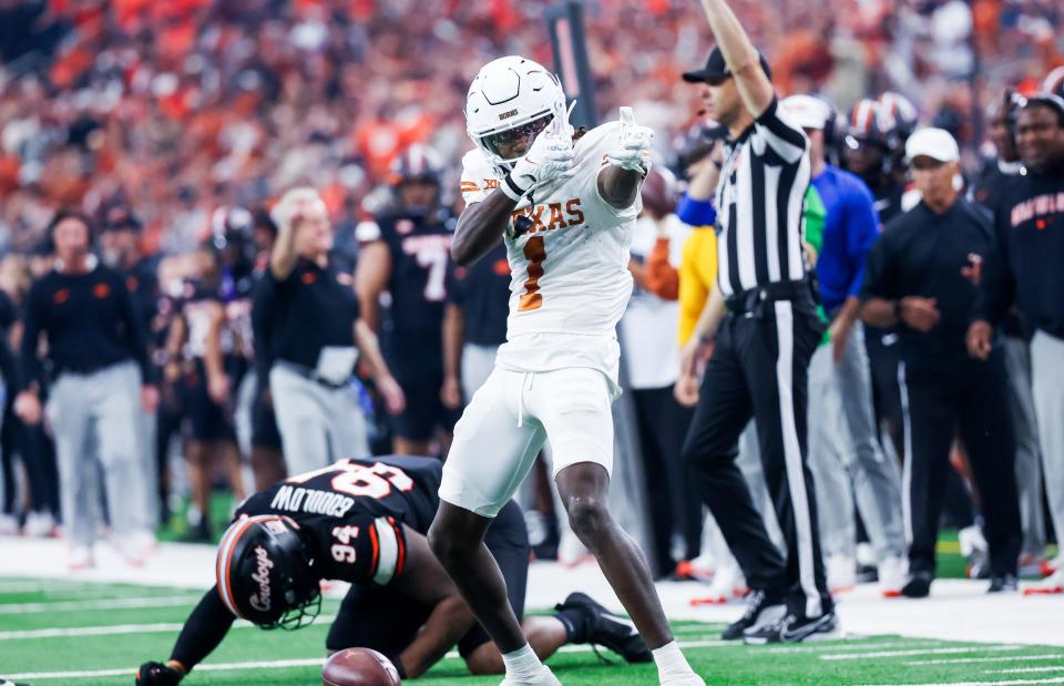 Texas Longhorns wide receiver Xavier Worthy (1) celebrates in front of Oklahoma State Cowboys defensive end Anthony Goodlow (94) during the first half at AT&T Stadium.