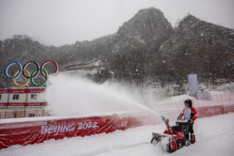 A worker clears snow off the women's downhill course as women's downhill training has been canceled due to snowfall during the 2022 Winter Olympic Games at the Yanqing National Alpine Skiing Centre in Yanqing on February 13, 2022. (DIMITAR DILKOFF/AFP via Getty Images)