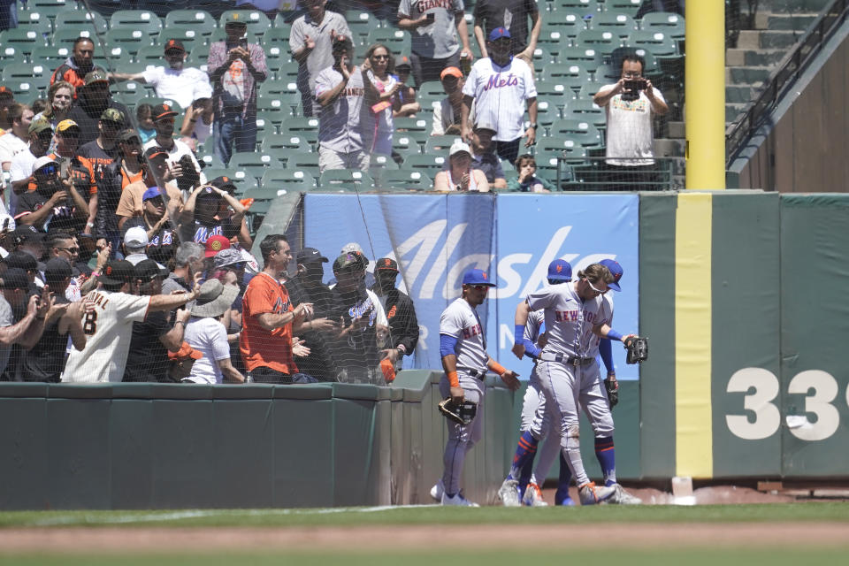 New York Mets right fielder Jeff McNeil, bottom right, is assisted by teammates after catching a foul ball hit by San Francisco Giants' Donovan Walton during the third inning of a baseball game in San Francisco, Wednesday, May 25, 2022. (AP Photo/Jeff Chiu)