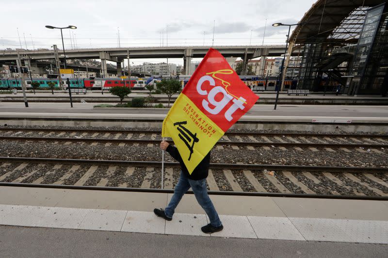 Un trabajador ferroviario francés de la SNCF en huelga sostiene una bandera sindical de la CGT mientras camina en un andén de la estación de ferrocarril de Niza durante un día de huelga nacional y protesta contra los planes de reforma de las pensiones del gobierno francés