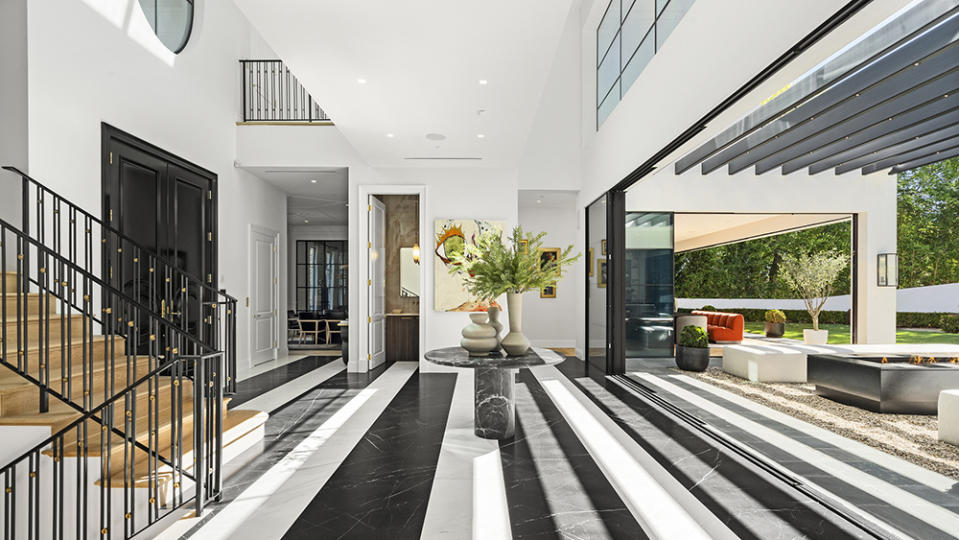 An entry foyer clad in black-and-white marble flooring spills out to a fire-pit lounge area.