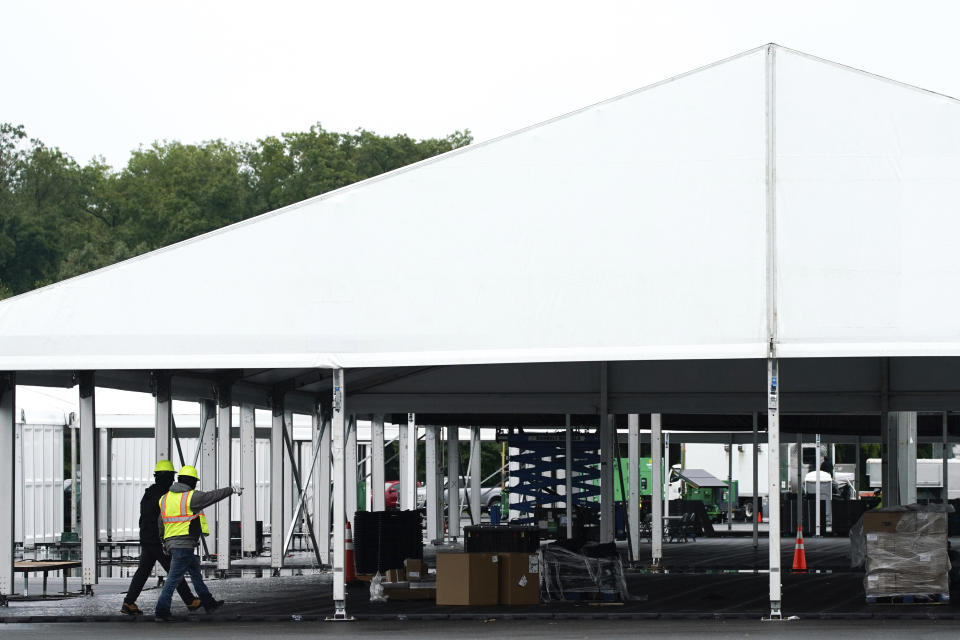 Workers disassemble hangar-sized tents, Tuesday, Oct. 4, 2022, in the parking lot of Orchard Beach in the Bronx borough of New York. Giant tents for temporarily housing migrants arriving in New York City are being moved to an island off Manhattan from a remote corner of the Bronx, after storms raised concerns over flooding at the original site. (AP Photo/Julia Nikhinson)