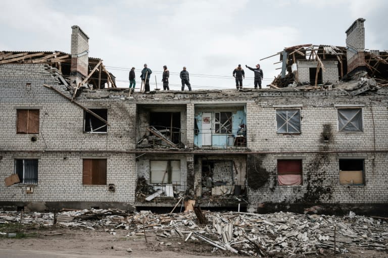 Workers clean rubble from a building destroyed by shelling weeks ago in Cherkaske, eastern Ukraine on May 11, 2022 (AFP/Yasuyoshi CHIBA)