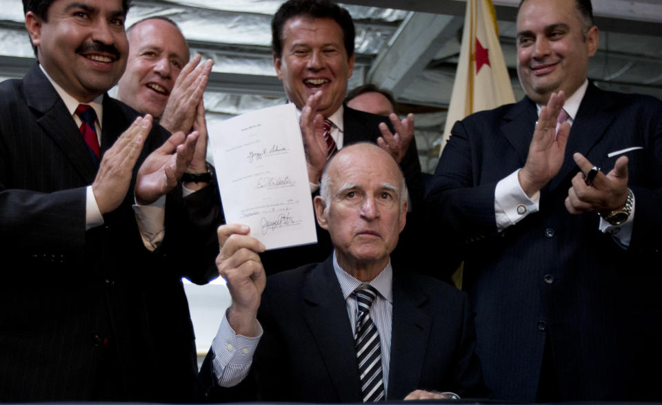 California Gov. Jerry Brown, below, holds up a newly-signed bill aimed at worker's compensation costs during a signing ceremony at a printing company in San Diego, Tuesday, Sept. 18, 2012. Looking on from right are California Assembly Speaker John Perez, California Assembly member Marty Block, California State Senate President pro Tem Darrell Steinberg, and California Assembly member Jose Solorio. Gov. Jerry Brown has signed a bill intended to reduce workers' compensation costs for California businesses while increasing benefits to injured workers. (AP Photo/Gregory Bull)