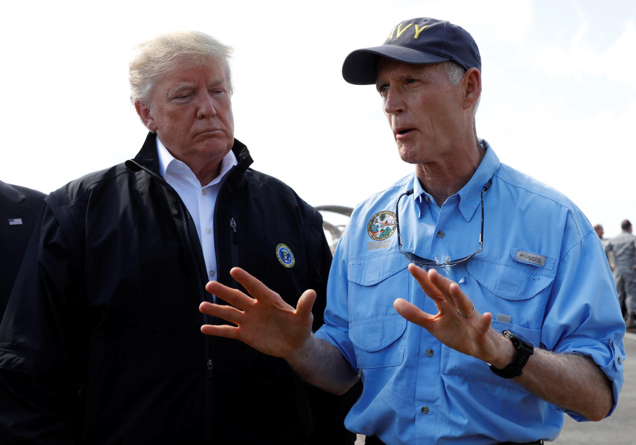 President Trump talks to Florida Gov. Rick Scott as the president arrives to tour storm damage from Hurricane Michael at Eglin Air Force Base, Fla. (Photo: Kevin Lamarque/Reuters)