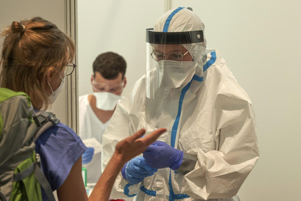 Travellers wait for the coronavirus test at the test center at the airport in Frankfurt, Germany, Saturday, Aug. 8, 2020. As of today, testing is mandatory for returnees from risk areas. (Thomas Frey/dpa via AP)