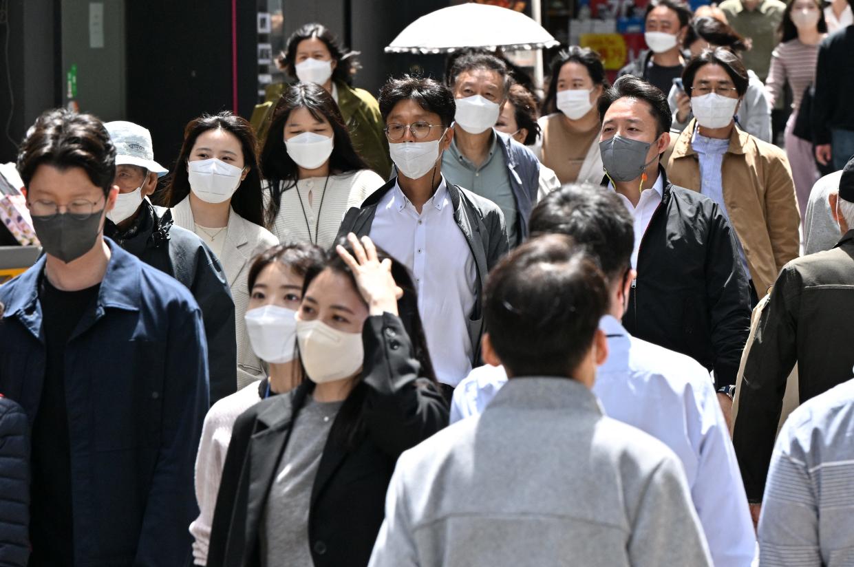 People wearing face masks walk through the Myeongdong shopping district in Seoul on April 29, 2022.