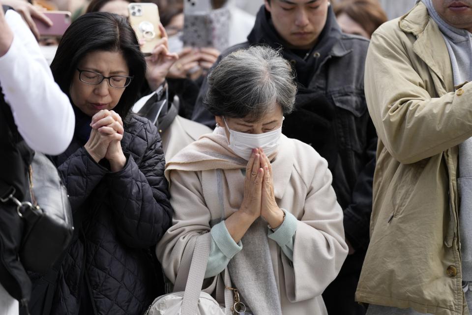 People pray when an annual tribute started at 2:46 p.m. for the victims of a 2011 disaster Monday, March 11, 2024, in Tokyo. Japan on Monday marked the 13th anniversary of the massive earthquake, tsunami and nuclear disaster that struck Japan's northeastern coast. (AP Photo/Eugene Hoshiko)