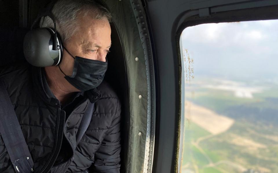 Israeli Defence Minister Benny Gantz wears a face mask as he looks out from the window of a helicopter during a tour of the Gaza border area, - Reuters/Reuters