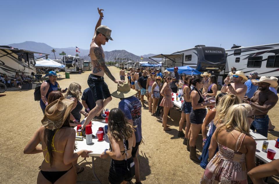 People stand around tables on a dirt field