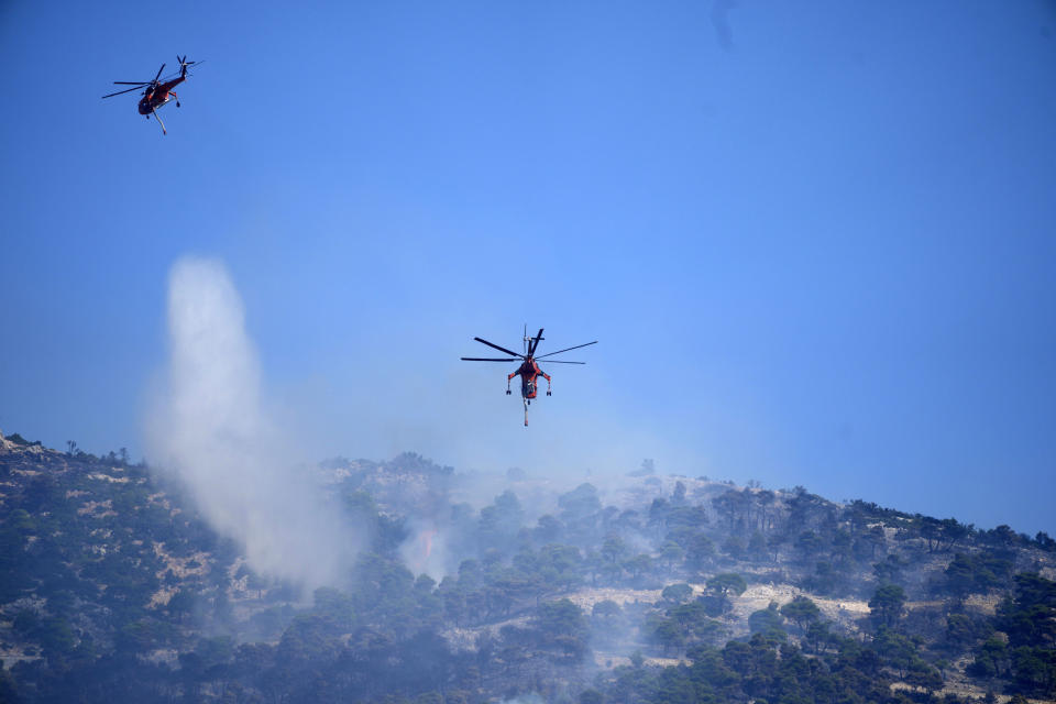 A helicopter drops water over a wildfire atop Mount Parnitha, in northwestern Athens, Greece, Thursday, Aug. 24, 2023. A major wildfire burning on the northwestern fringes of the Greek capital has torched homes and is now threatening the heart of a national park of Parnitha, one of the last green areas near the Greek capital. (AP Photo/Thanassis Stavrakis)