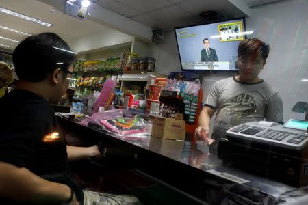 Men stand in a store as Thailand Prime Minister Prayuth Chan-ocha is seen on a TV during his weekly broadcast in Bangkok, Thailand, May 19, 2017. REUTERS/Jorge Silva