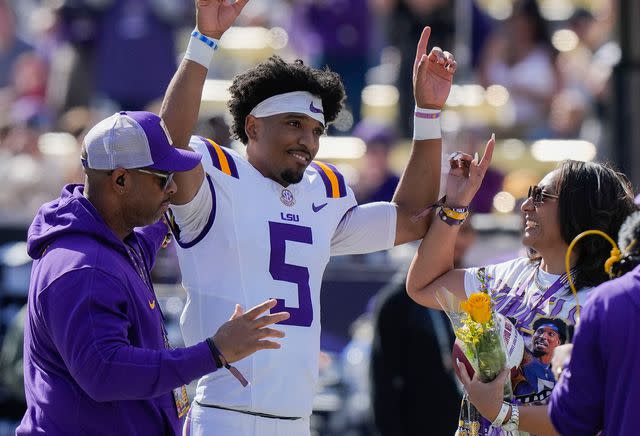 <p>Gerald Herbert/AP</p> Jayden Daniels celebrates with his parents on senior day on November 25, 2023.