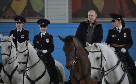 Russian President Vladimir Putin (2nd R) rides a horse as he attends a meeting with female officers of a mounted police unit to congratulate them on the upcoming International Women's Day in Moscow, Russia March 7, 2019. Sputnik/Alexei Nikolsky/Kremlin via REUTERS