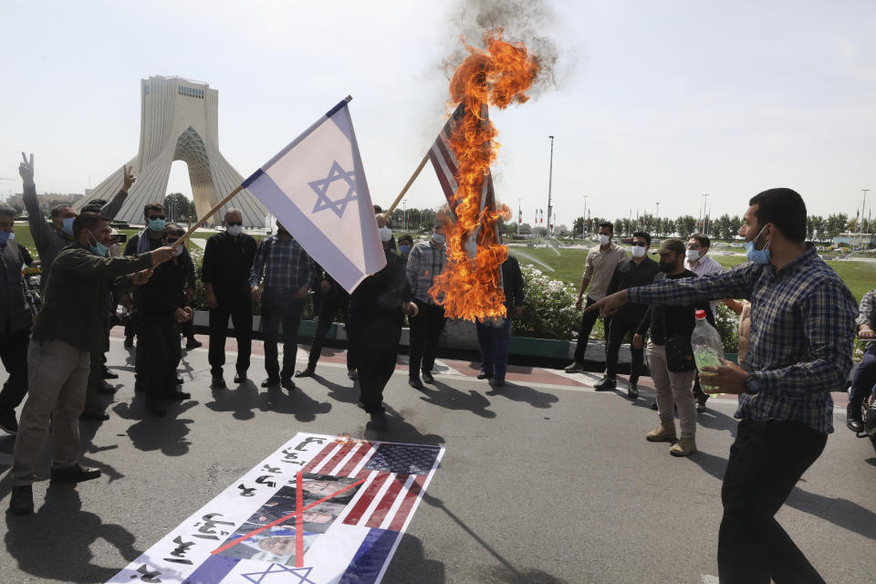 Demonstrators burn representations of Israeli and U.S flags during the annual Al-Quds, or Jerusalem, Day rally, with the Azadi (Freedom) monument tower seen at left, in Tehran, Iran, Friday, May 7, 2021. Iran held a limited anti-Israeli rally amid the coronavirus pandemic to mark the Quds Day. After the late Ayatollah Khomeini, leader of the Islamic Revolution and founder of present-day Iran, toppled the pro-Western Shah in 1979, he declared the last Friday of the Muslim holy month of Ramadan as an international day of struggle against Israel and for the liberation of Jerusalem. (AP Photo/Vahid Salemi)