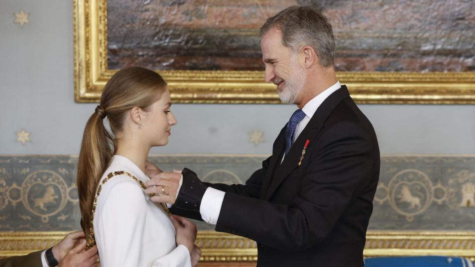 princess leonor stands facing king felipe vi who places a golden necklace on her